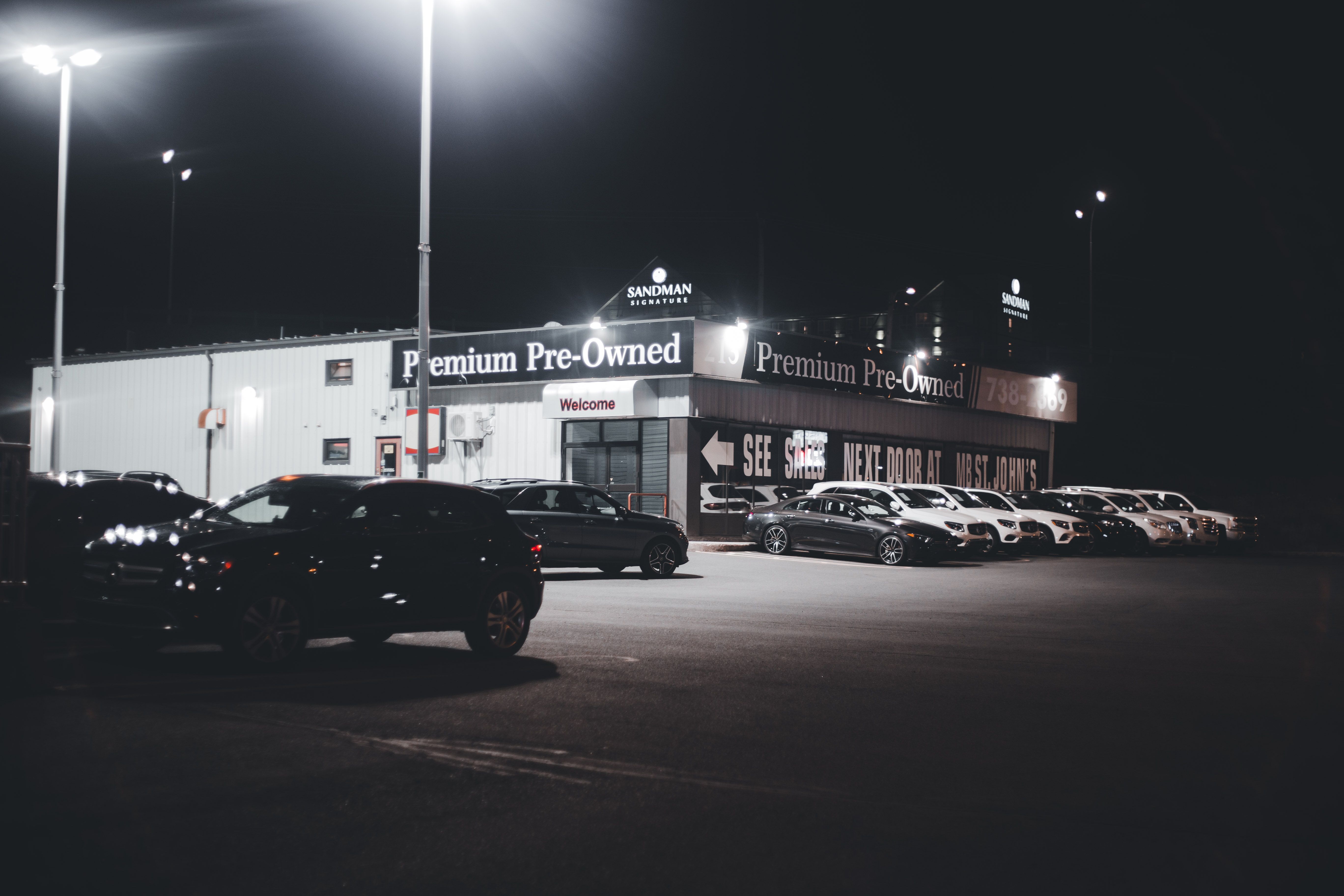 Illuminated car dealership lot showcasing pre-owned vehicles at night