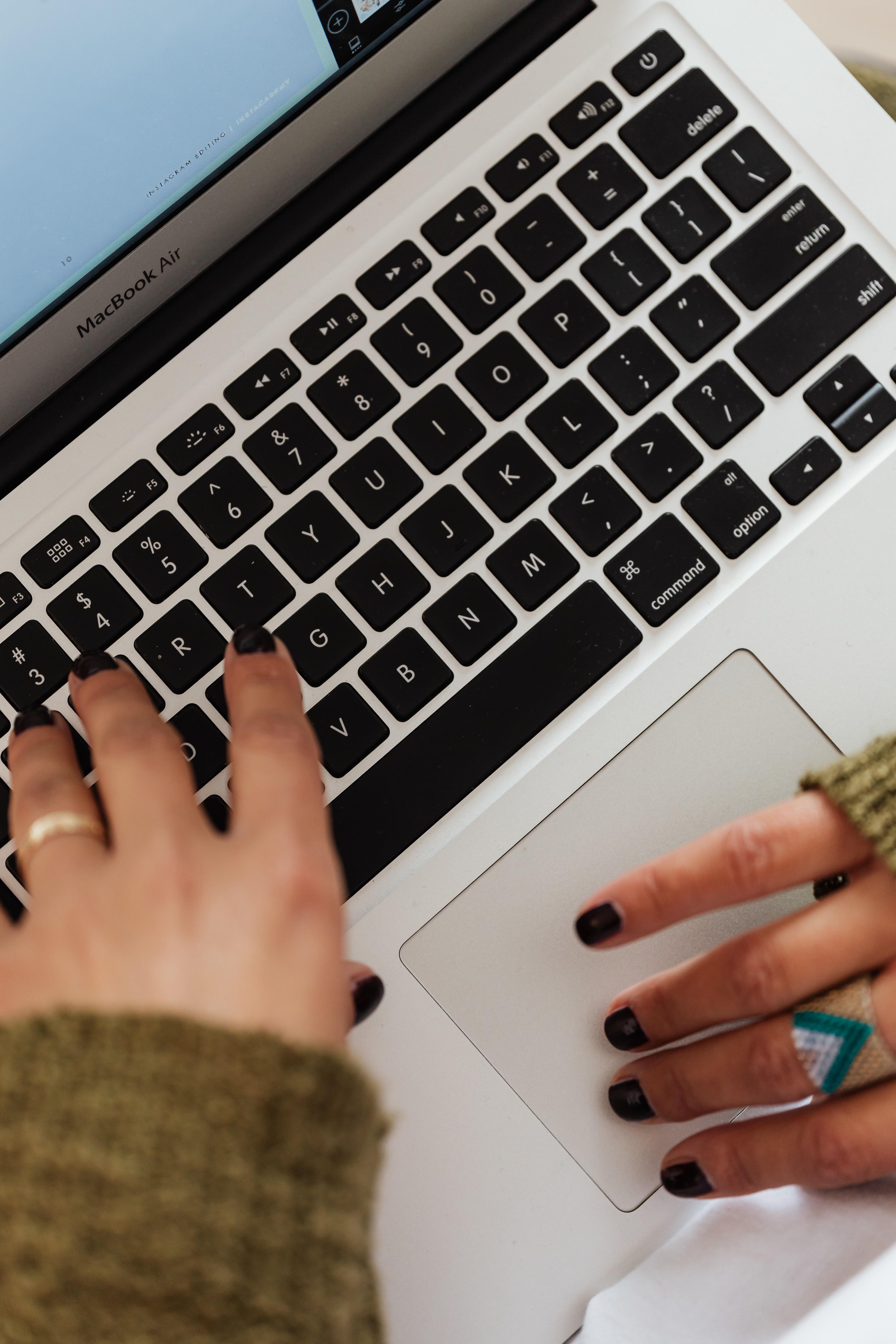 Close-up of hands typing on a laptop keyboard while writing content